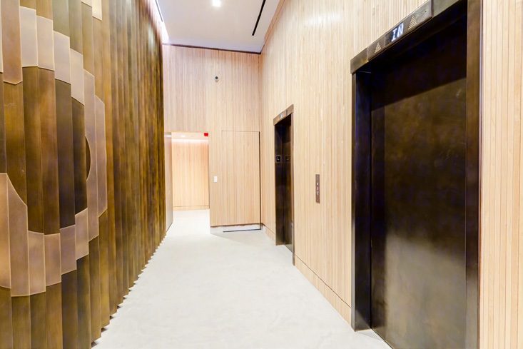 Elevator corridor with a bronze-toned feature wall