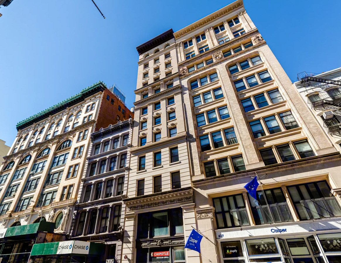 The limestone facade of 625 Broadway between its taller neighbors