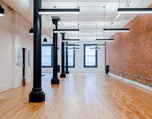Row of black cast-iron columns beside an exposed brick wall