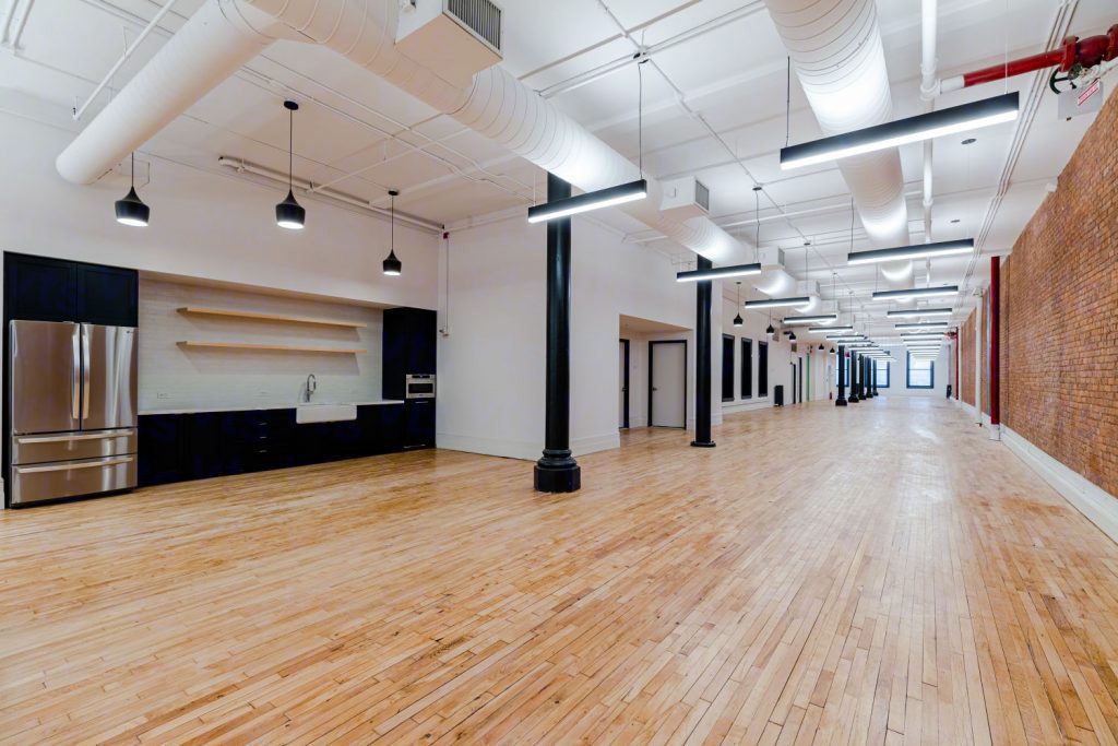 3rd floor kitchen along one wall of a long open loft with cast-iron columns
