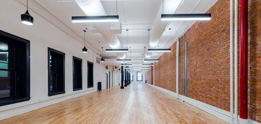 Long 3rd floor loft with windows on one side and exposed brick on the other