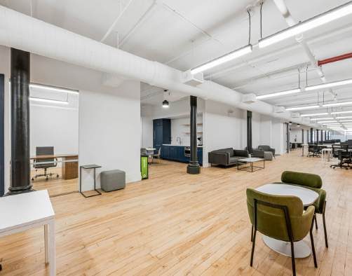 Collaborative seating area with lounge chairs and workstations beyond