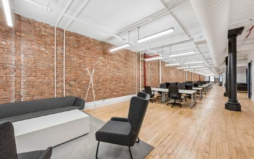 5th floor lounge seating and workstations along an exposed brick wall