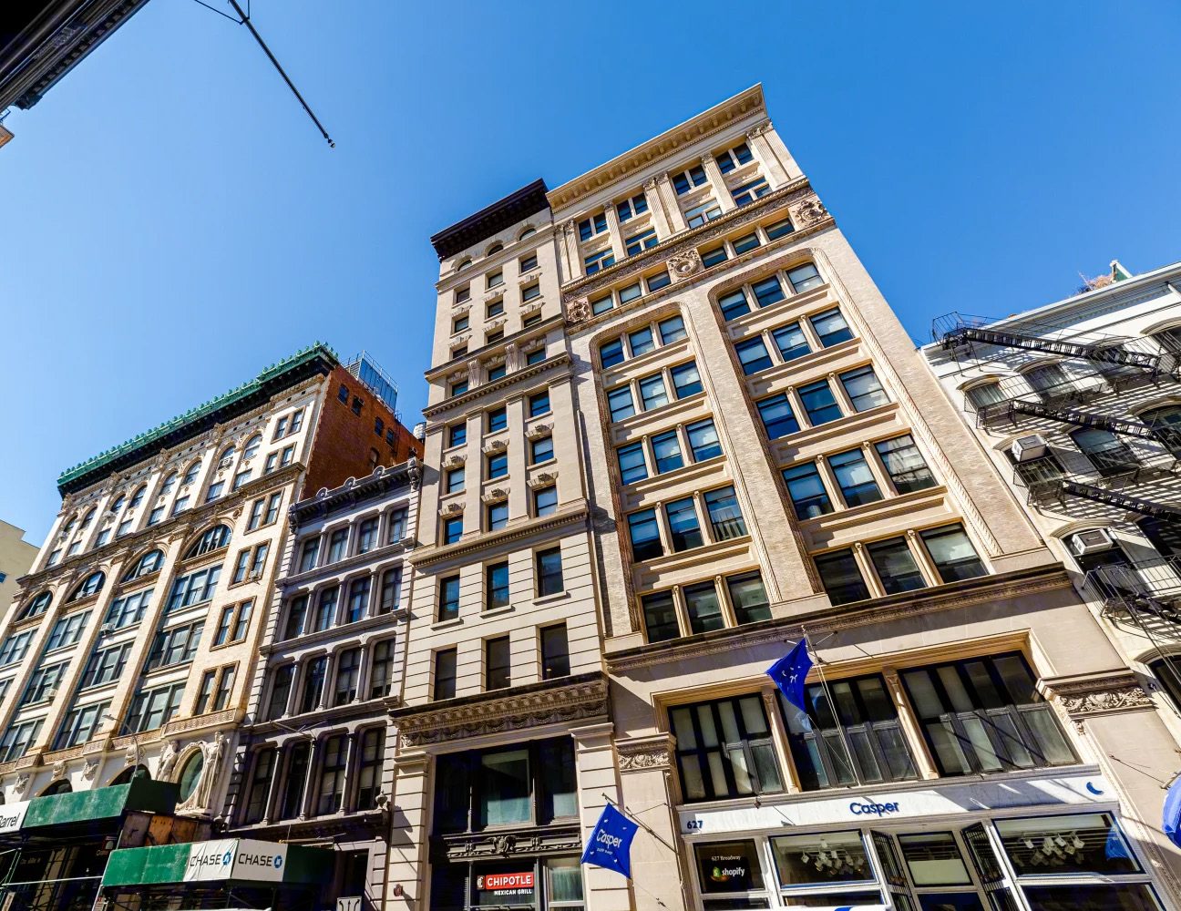625 Broadway, a narrow limestone loft building with an ornate cornice, seen from the street below