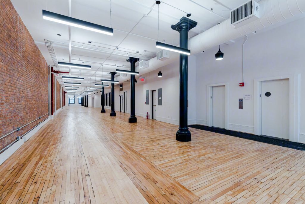Loft floor with exposed brick wall, hardwood floor and cast-iron columns