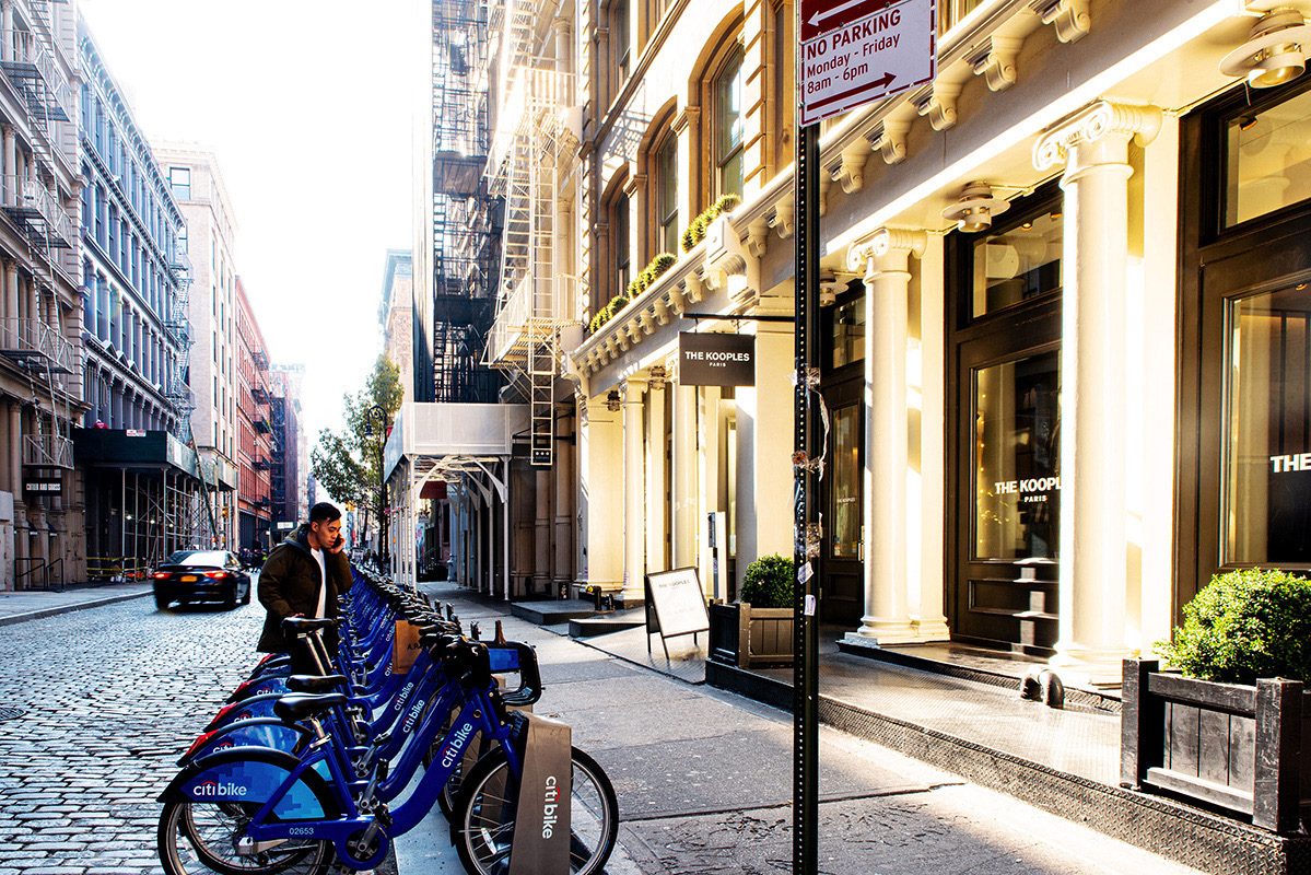 Cobblestone street lined with cast-iron buildings and a Citi Bike dock