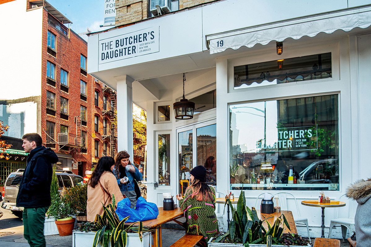 People at outdoor tables in front of The Butcher's Daughter cafe